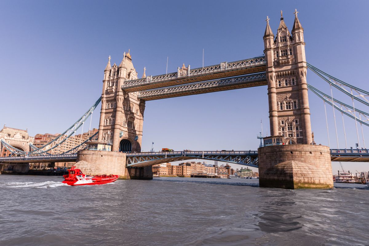 A red Thames Rockets speedboat passes under Tower Bridge in London.